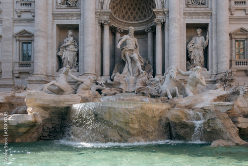 Close-up of one of the most famous landmarks in the world - Trevi Fountain in Rome in bright sunlight with water basin in the foreground.