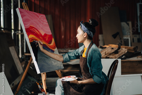 Asian Female Artist Draws create art piece with palette and brush painting at studio.