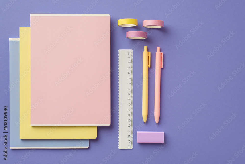 Back to school concept. Top view photo of colorful school supplies stack of notebooks pens ruler eraser and adhesive tape on isolated violet background Back to school concept. Top view photo of colorful school supplies stack of notebooks pens ruler eraser and adhesive tape on isolated violet background