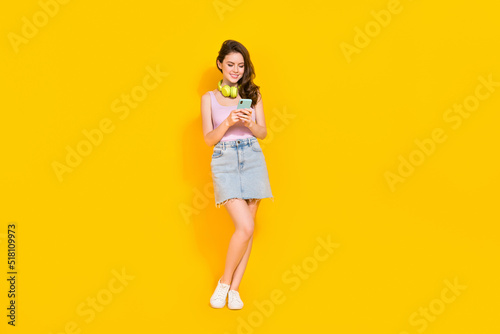 Full length photo of cute shiny woman wear pink top looking for good music isolated yellow color background