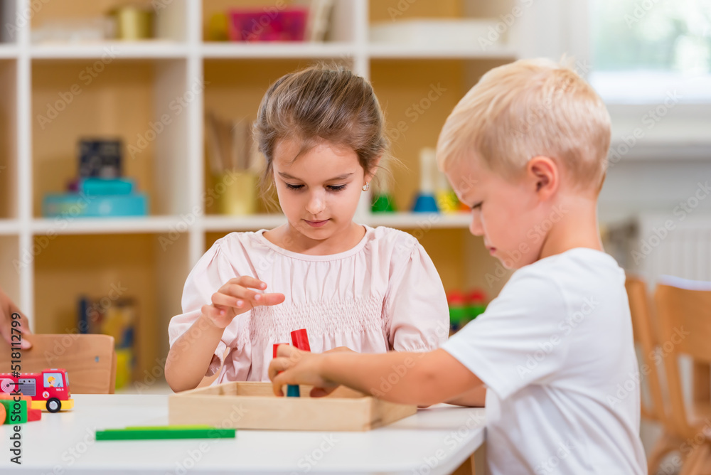 A couple of children are playing with colorful wooden toys at kindergarten. They are concentrated on their play. A couple of children are playing with colorful wooden toys at kindergarten. They are concentrated on their play.
