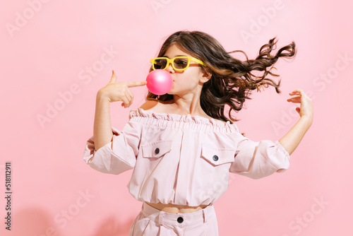 Φωτογραφία Fashionable little girl, kid posing isolated over pink color background