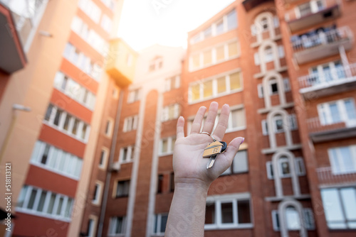 Beautiful  female hands hold the keys to the new apartment on the background of the building © RomanR
