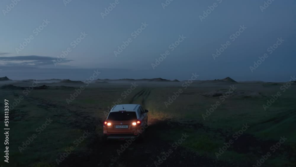 Car reversing on grassy offroad path at dusk. Adventurous wandering in unknown Nordic landscape. Iceland Car reversing on grassy offroad path at dusk. Adventurous wandering in unknown Nordic landscape. Iceland