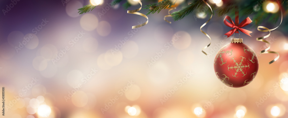 A red Christmas bauble hanging down from a Christmas tree with lights and a blurred festive banner background. A red Christmas bauble hanging down from a Christmas tree with lights and a blurred festive banner background.