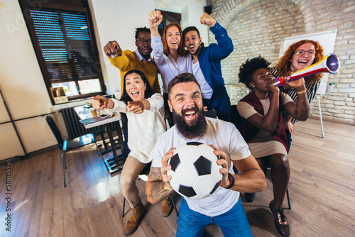 Happy casual business people or football fans watching soccer on tv and celebrating victory. Friendship, sports and entertainment concept. © Mediteraneo