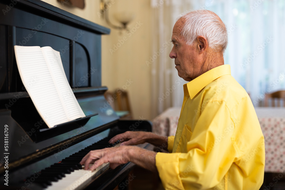 Man practicing playing piano in the living room of his home after retirement from work