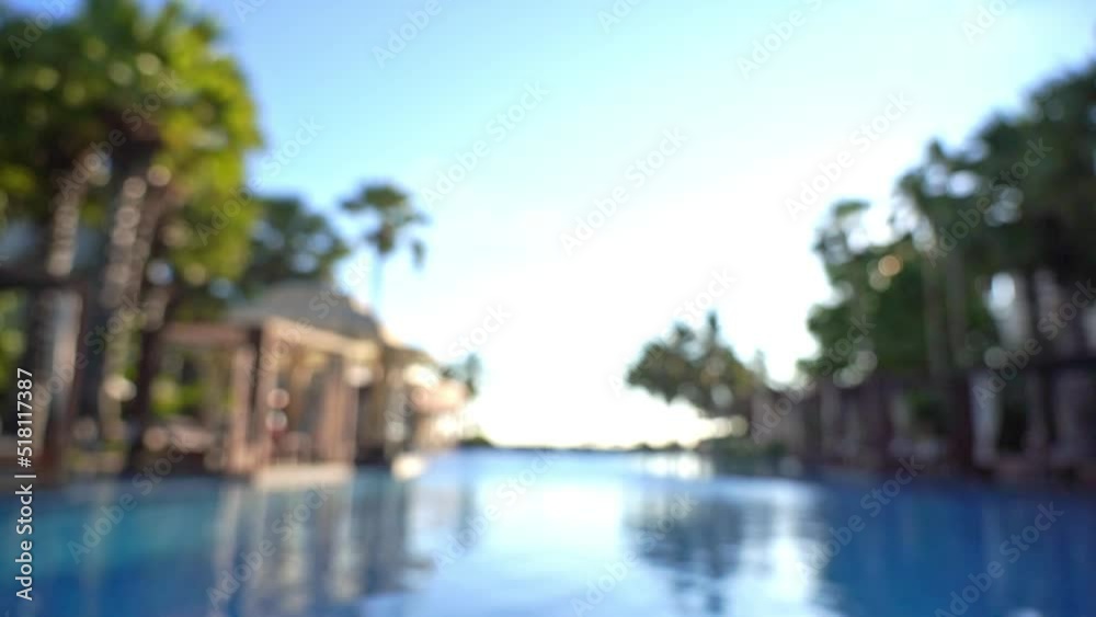 Blurred view from inside hotel's outroor lounge swimming pool with tropical palms and rest area Blurred view from inside hotel's outroor lounge swimming pool with tropical palms and rest area