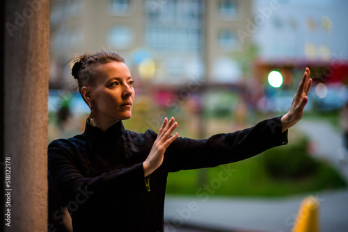 Asian woman trains tai chi in the city, chinese martial arts, healthy lifestyle concept.