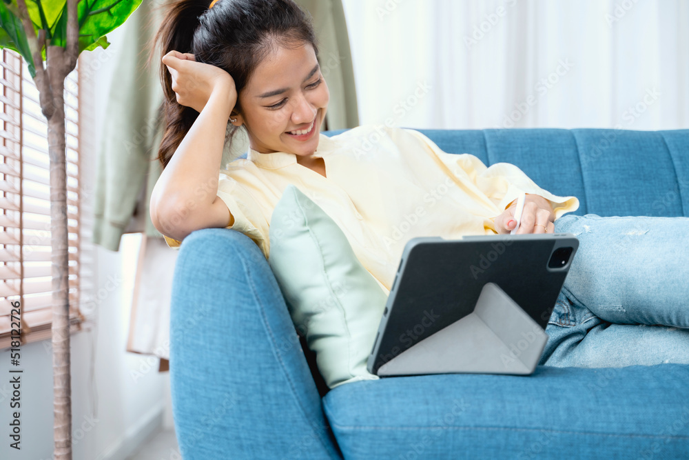 Asian woman happily using tablet to watch comedy series at home Asian woman happily using tablet to watch comedy series at home