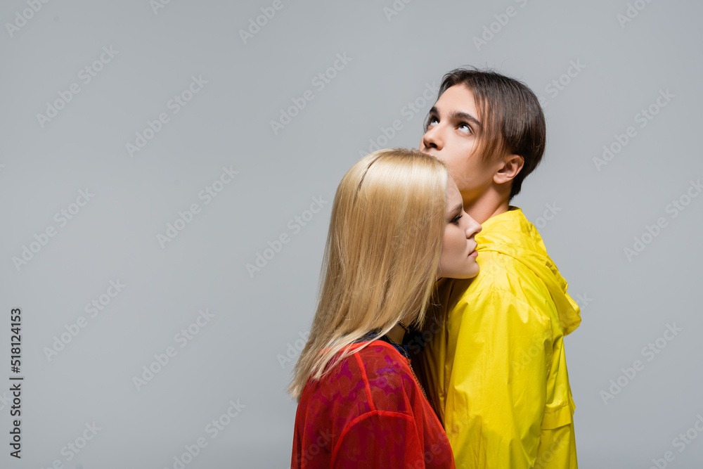 Blonde woman standing near boyfriend in windbreaker isolated on grey. Blonde woman standing near boyfriend in windbreaker isolated on grey.