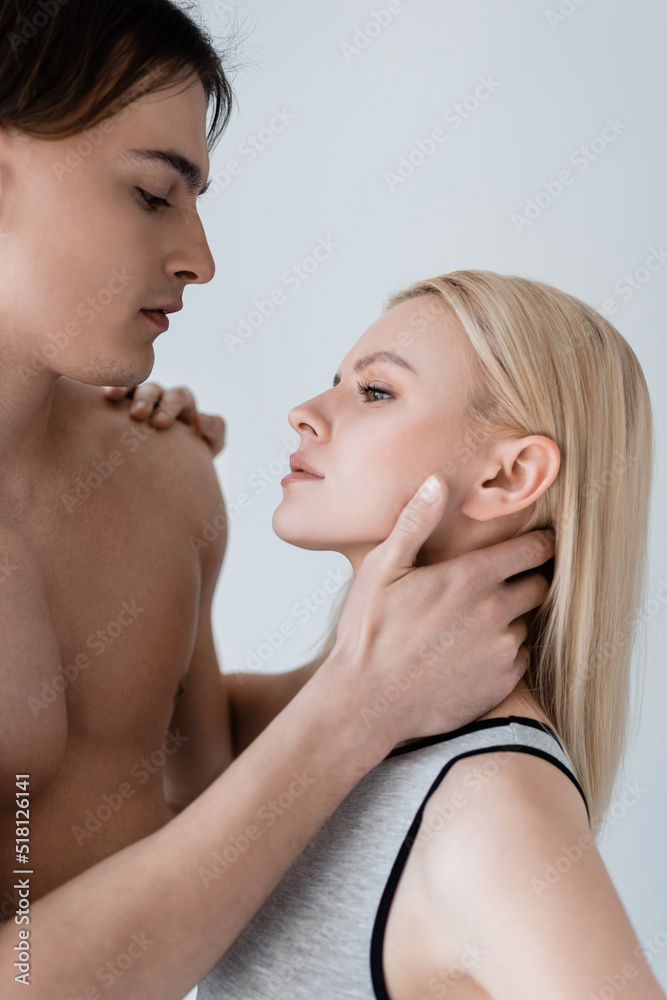 Side view of sexy man touching blonde girlfriend isolated on grey.