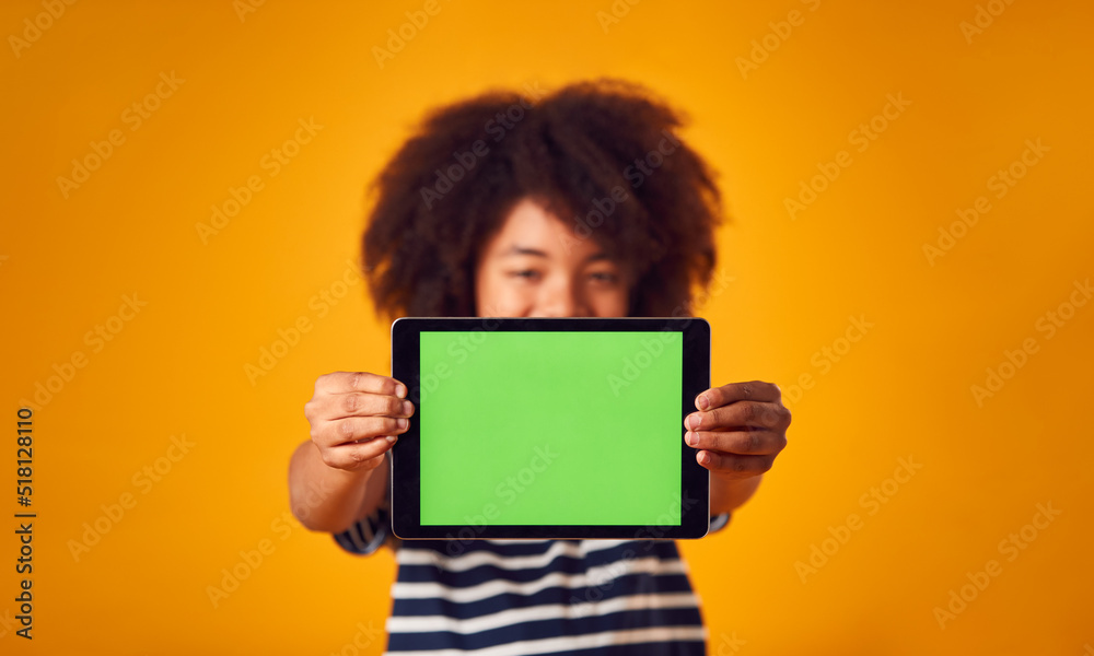 Studio Portrait Of Boy Using Digital Tablet With Green Screen Against Yellow Background Studio Portrait Of Boy Using Digital Tablet With Green Screen Against Yellow Background