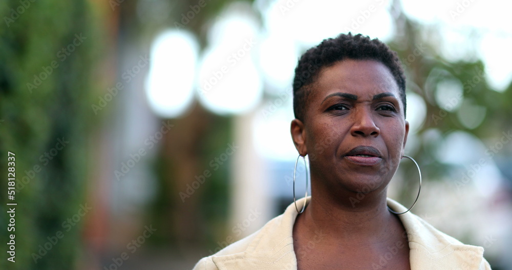 Pensive African woman walking outside. 40s Thoughtful black person thinking Pensive African woman walking outside. 40s Thoughtful black person thinking