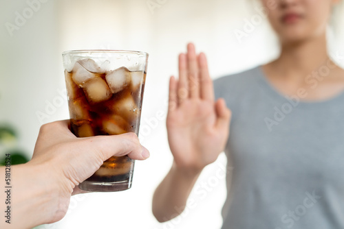 Close up slim woman hand push out say no avoid and reject her favorite cola soft drink high sweet sugar for good health diet and calories control
