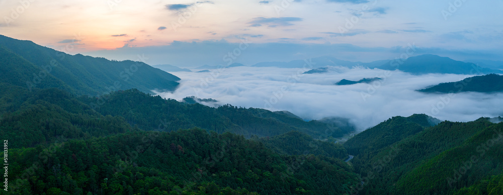 Panoramic view looking down on early morning fog in mountains as sun rises