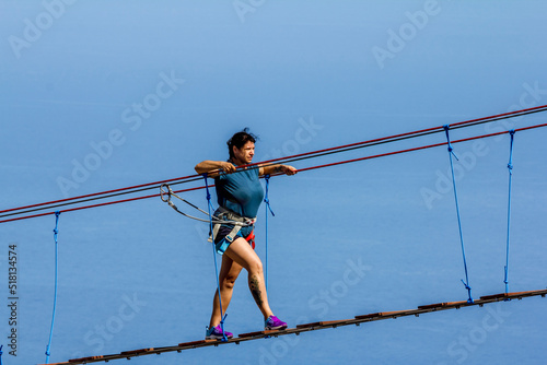Young woman crossing a chasm on a rope bridge