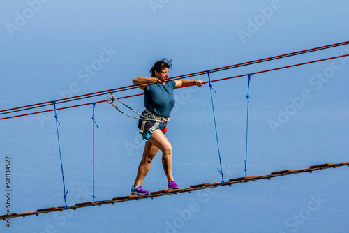 Young woman crossing a chasm on a rope bridge