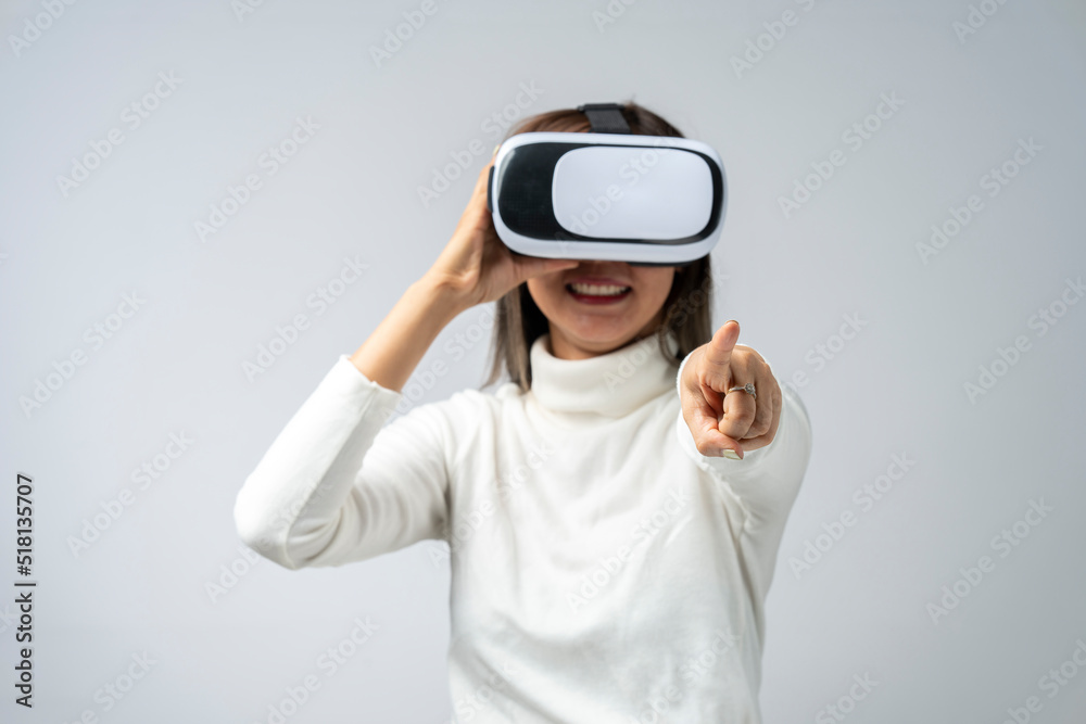 Asian woman wearing VR glasses in studio with white background with using virtual reality headset or VR glass isolate on gray background