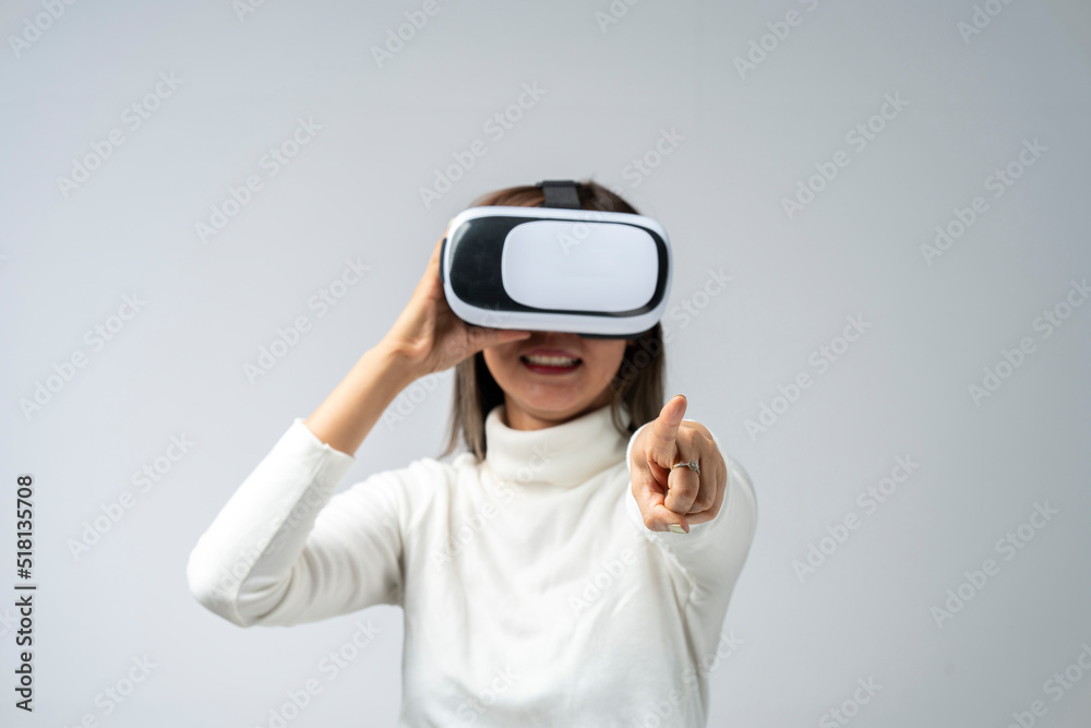 Asian woman wearing VR glasses in studio with white background with using virtual reality headset or VR glass isolate on gray background Asian woman wearing VR glasses in studio with white background with using virtual reality headset or VR glass isolate on gray background