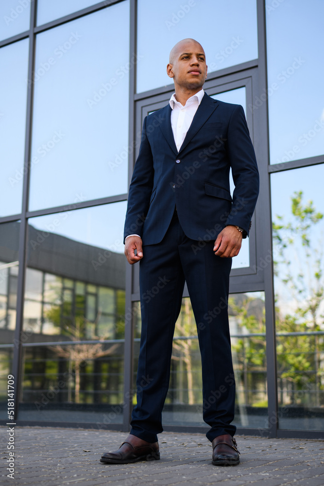 Elegant african american businessman in formal wear standing near building on street Elegant african american businessman in formal wear standing near building on street