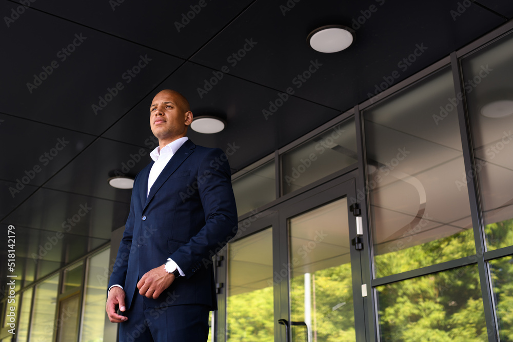 Young african american manager in suit standing near building outdoors Young african american manager in suit standing near building outdoors