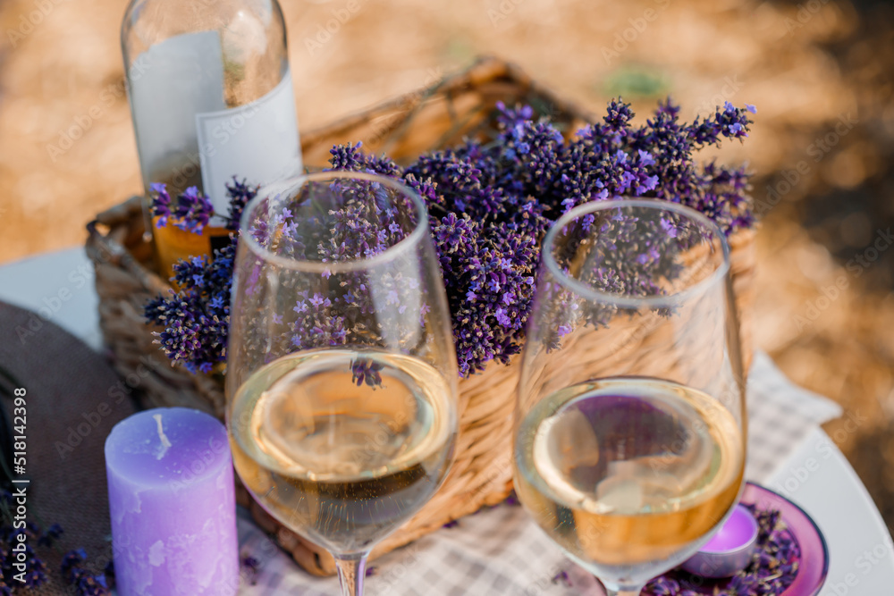 Two Glasses of white wine and bottle in a lavender field in Provance. Violet flowers on the background