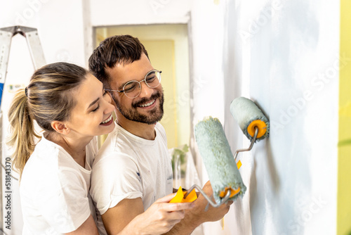 Young couple painting wall in their home.