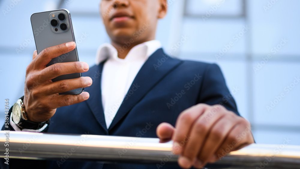 Partial view of african american real estate agent using smartphone near building, banner shot Partial view of african american real estate agent using smartphone near building, banner shot