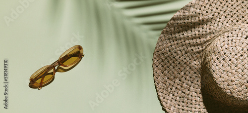 Photography Summer flat lay with straw hat and sunglasses on green background with palm leaf shadow, sun and sunlight