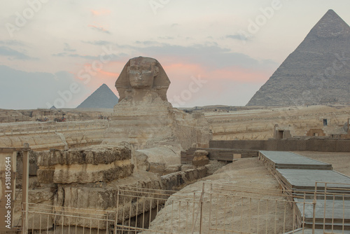 Landscape with Egyptian pyramids, Great Sphinx and silhouettes Ancient symbols and landmarks of Egypt for your travel concep in golden sunlight. The Sphinx in Giza pyramid complex at sunset