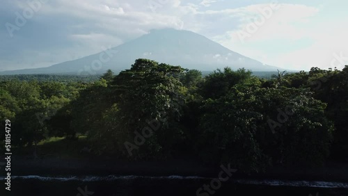 mount agung reveals on the shoreline green rainforest photo