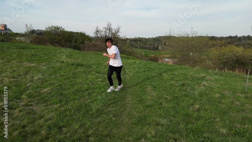 Aerial View of Young Man Running and Doing Somersault in Green Outdoor Field, Slow Motion photo