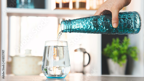 Tableau sur toile Pouring water from water bottle into glass in kitchen