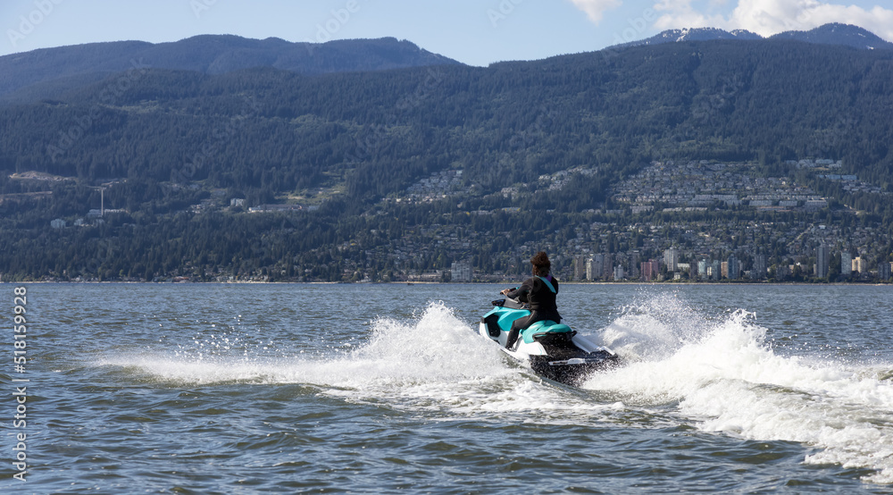 Adventurous Caucasian Woman on Water Scooter riding in the Ocean. Modern City and mountains in background. Downtown Vancouver, British Columbia, Canada. Adventurous Caucasian Woman on Water Scooter riding in the Ocean. Modern City and mountains in background. Downtown Vancouver, British Columbia, Canada.