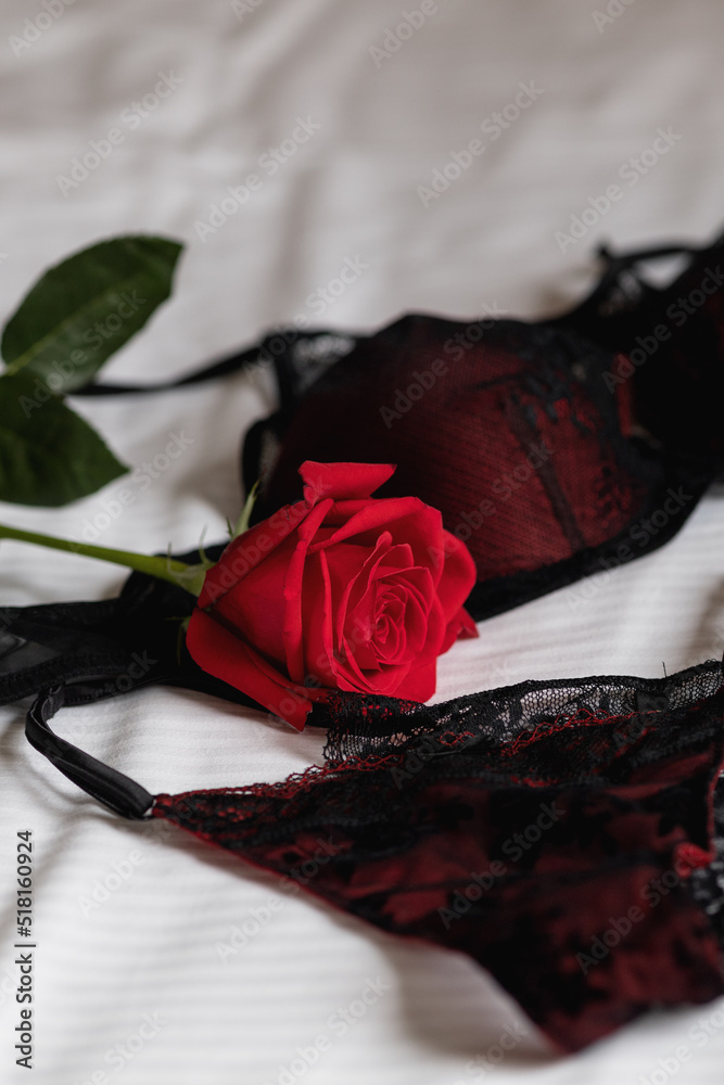 thin lace black underwear panties and bra and red rose are lying on the bed  Stock Photo