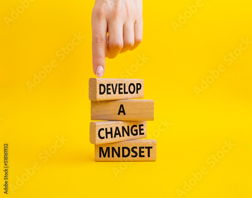 Develop a change mindset symbol. Concept words Develop a change mindset on wooden blocks. Beautiful yellow background. Businessman hand. Business and Develop a change mindset concept. Copy space.