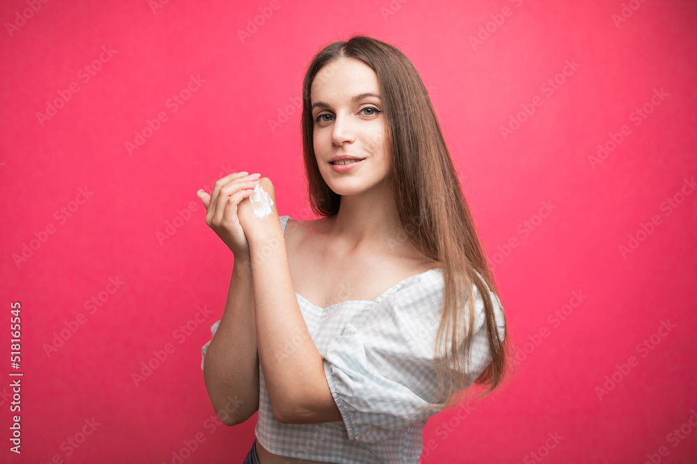 Young woman applying hand cream on pink background Young woman applying hand cream on pink background