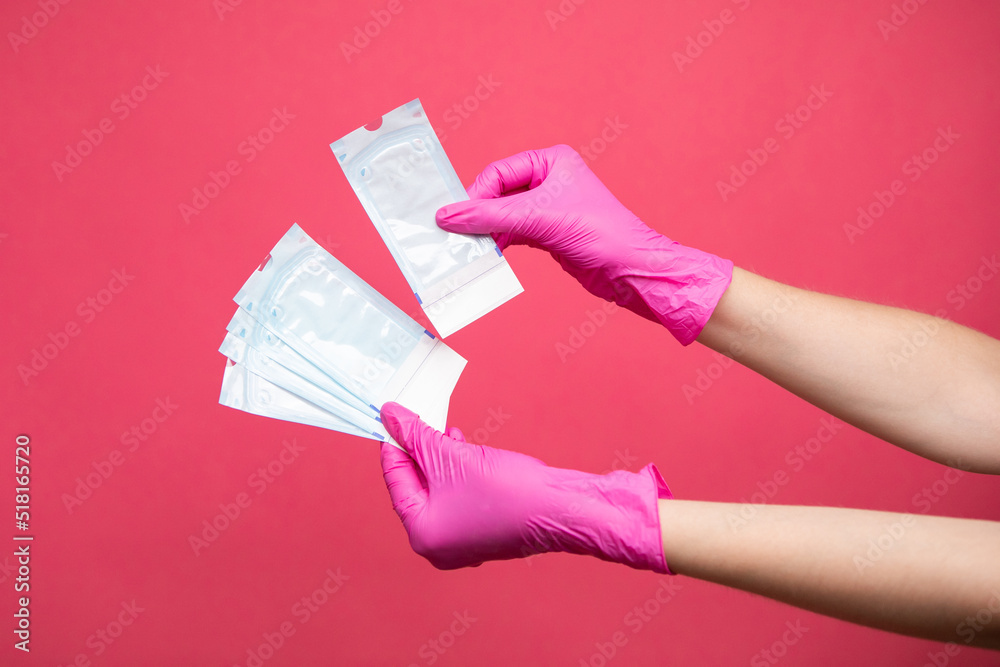 Hand holding sterilization envelopes for manicure in gloves Hand holding sterilization envelopes for manicure in gloves