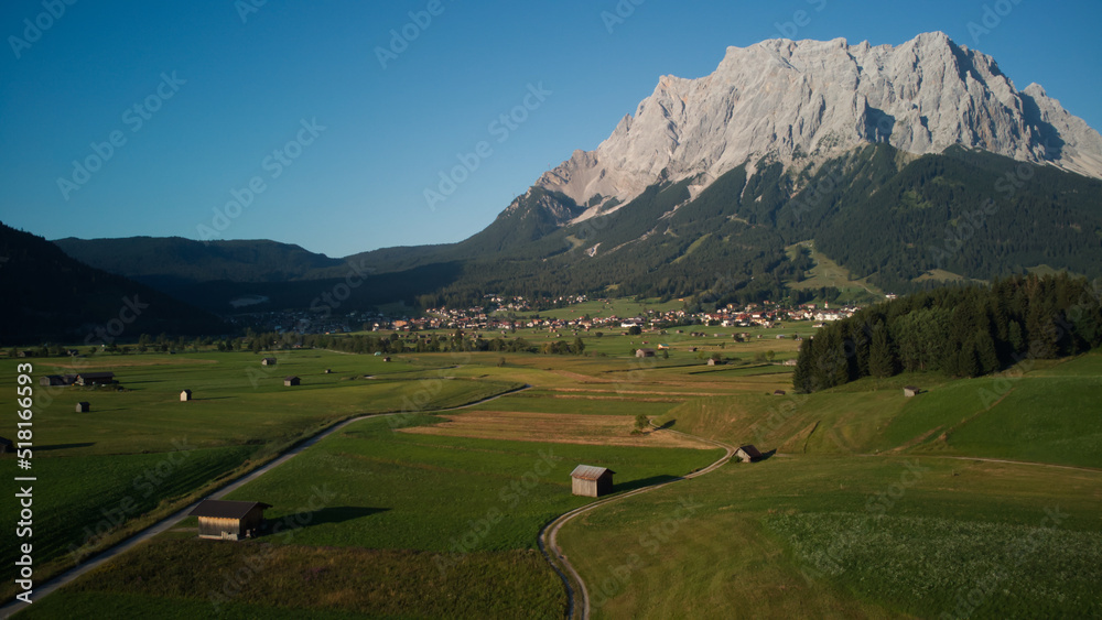 Aerial view of idyllic rolling hills spring landscape in the Alps with lush green wood houses.