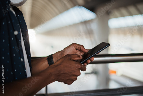 Close up shot of african man using social media on his phone. He is at a train station.