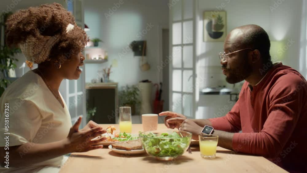 Arc shot of emotional African American couple arguing and blaming each other while having dinner in evening at home