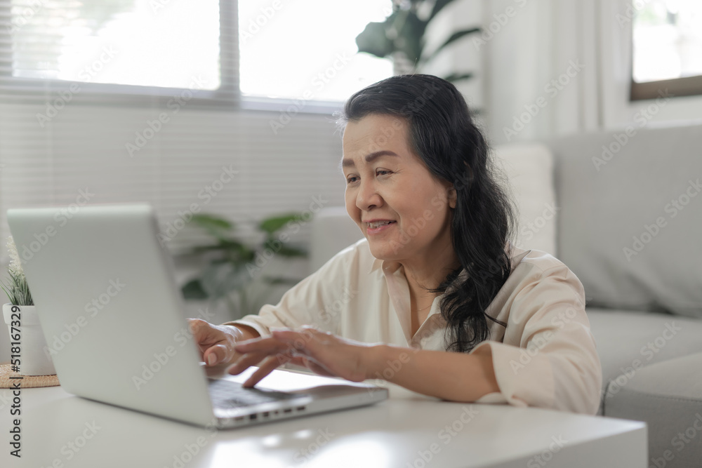 Happy and cheerful older lady Mature asian woman reading good news at laptop. senior business woman and technology concept. Happy and cheerful older lady Mature asian woman reading good news at laptop. senior business woman and technology concept.