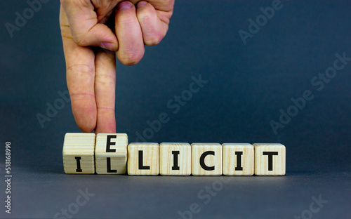 Illicit or elicit symbol. Businessman turns wooden cubes and changes the concept word Illicit to Elicit. Beautiful grey table grey background. Business illicit or elicit concept. Copy space.