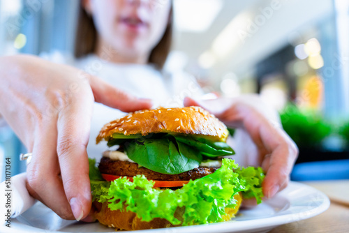 Vegan burger healthy vegetarian hamburger. Salad, avocado, vegetable on veggie sandwich eating cute woman. Vegetarian hamburger healthy diet food.