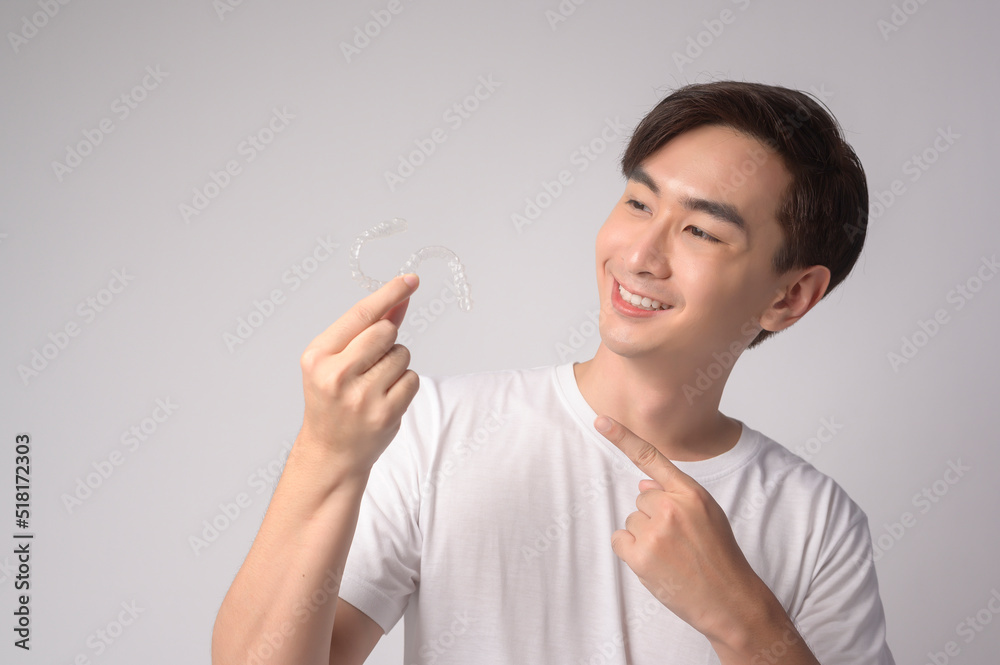 Young smiling man holding invisalign braces over white background studio, dental healthcare and Orthodontic concept.. Young smiling man holding invisalign braces over white background studio, dental healthcare and Orthodontic concept..
