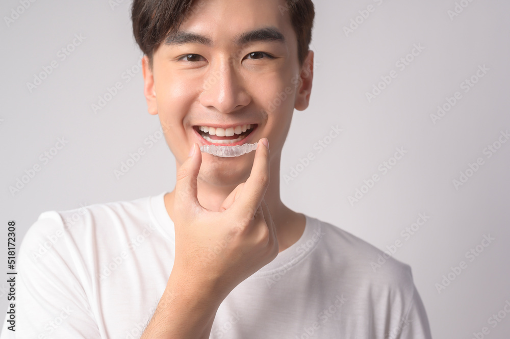 Young smiling man holding invisalign braces over white background studio, dental healthcare and Orthodontic concept.. Young smiling man holding invisalign braces over white background studio, dental healthcare and Orthodontic concept..
