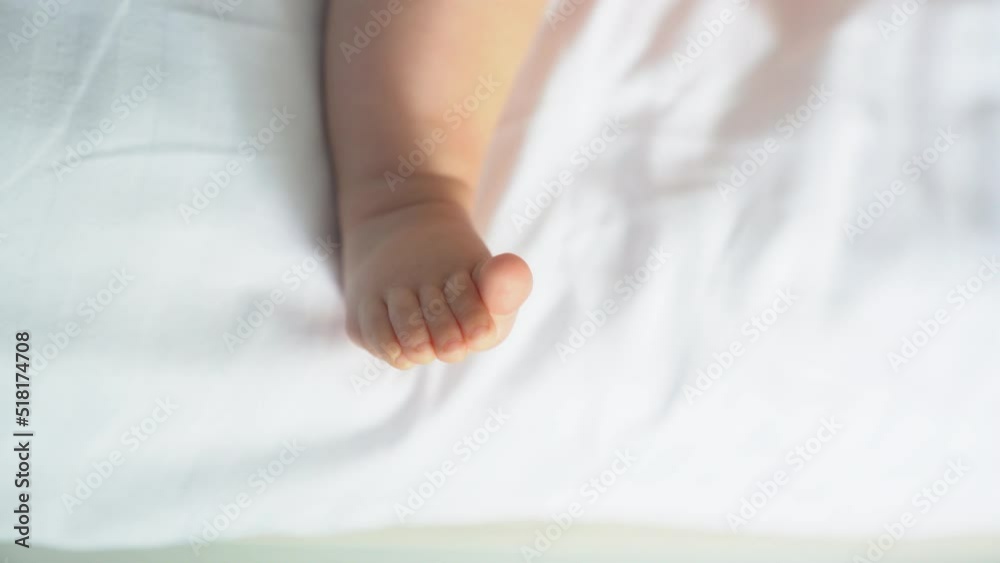The legs of a newborn baby move on a white sheet. The child's legs are two in the frame, then one is removed. The concept of motherhood, family, birth. High quality 4k footage The legs of a newborn baby move on a white sheet. The child's legs are two in the frame, then one is removed. The concept of motherhood, family, birth. High quality 4k footage