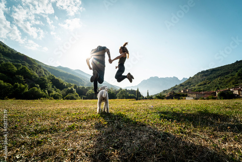 Young happy couple in love jumping on the mountain with their dog