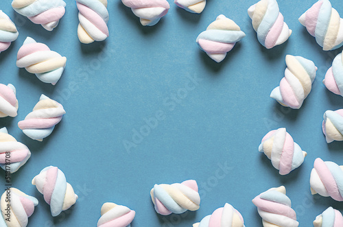 White, yellow, pink, and light blue marshmallows on light blue background with copy space. 